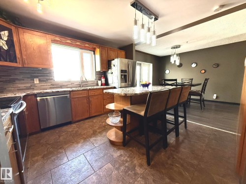 Kitchen featuring granite countertops, wood cabinetry, stainless steel appliances, and a mosaic tile backsplash - 4508 57 Avenue, Lamont, AB - Indoor Photo Showing Kitchen