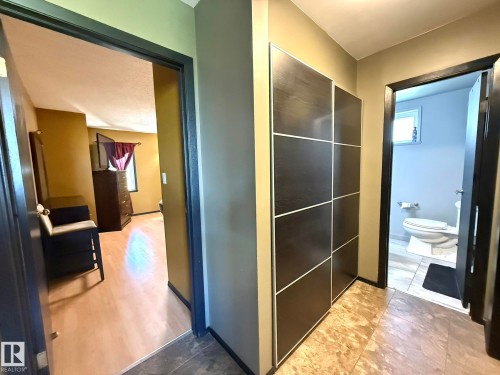 Hallway featuring a built-in dark wood-finish storage unit with white trim and a combination of light and dark tile flooring - 4508 57 Avenue, Lamont, AB - Indoor Photo Showing Other Room