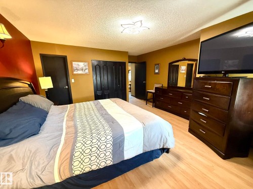 Bedroom featuring wood-finish flooring, dark paneled doors, and a ceiling-mounted light fixture - 4508 57 Avenue, Lamont, AB - Indoor Photo Showing Bedroom
