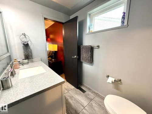 Bathroom with light gray walls, a granite-finish countertop, and a single-basin sink - 4508 57 Avenue, Lamont, AB - Indoor Photo Showing Bathroom