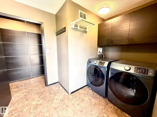 Dedicated utility space featuring overhead cabinetry and a mounted drying rack - 4508 57 Avenue, Lamont, AB - Indoor Photo Showing Laundry Room