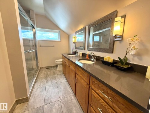 Bathroom featuring a glass-enclosed shower, a double vanity with ample storage, a gray countertop, and contemporary wall sconces - 4508 57 Avenue, Lamont, AB - Indoor Photo Showing Bathroom
