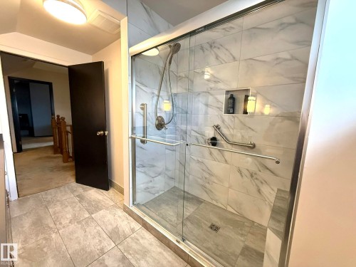 Spacious walk-in shower featuring glass enclosure, large format marble-look tile, built-in niche, and brushed nickel fixtures - 4508 57 Avenue, Lamont, AB - Indoor Photo Showing Bathroom
