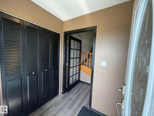 Entryway featuring wood-finish flooring, a decorative glass front door, black louvered bifold closet doors, and a paneled interior door - 4508 57 Avenue, Lamont, AB - Indoor Photo Showing Other Room