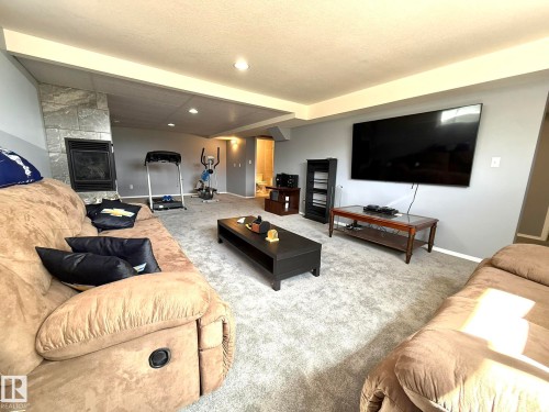 Spacious room featuring light gray carpeting, neutral wall colors, recessed lighting, and a stone-clad fireplace - 4508 57 Avenue, Lamont, AB - Indoor Photo Showing Living Room