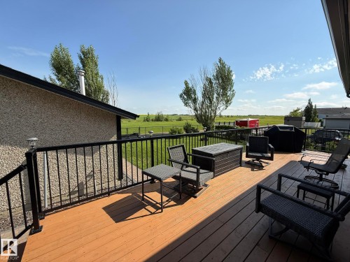 Expansive composite deck featuring warm wood-finish decking, black metal railing with horizontal spindles, and multiple seating and entertaining zones - 4508 57 Avenue, Lamont, AB - Outdoor With Deck Patio Veranda With Exterior