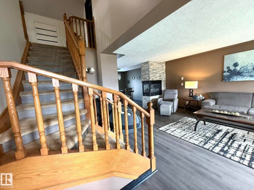 Two-story entry foyer featuring a light-toned wood staircase with carpeted treads - 4508 57 Avenue, Lamont, AB - Indoor With Fireplace
