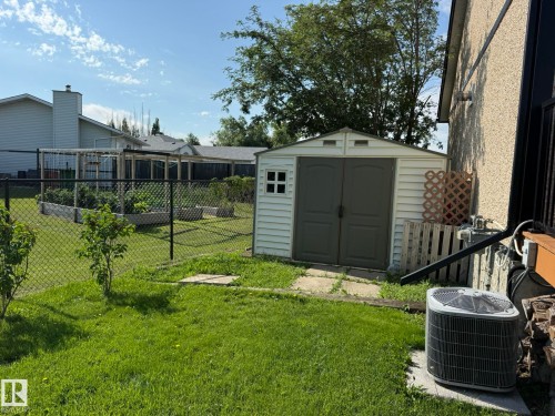 Landscaped backyard featuring a storage shed, chain link fencing, a garden area with raised beds, and mature trees - 4508 57 Avenue, Lamont, AB - Outdoor With Exterior
