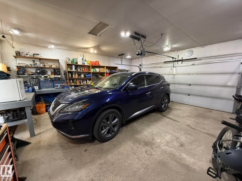 Attached garage space featuring a concrete floor, overhead lighting, and a white panel garage door with an automatic opener - 4508 57 Avenue, Lamont, AB - Indoor Photo Showing Garage