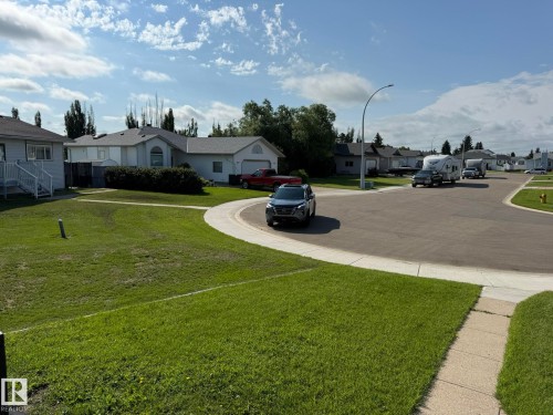 Property featuring a spacious front lawn and a paved driveway leading to an attached garage - 4508 57 Avenue, Lamont, AB - Outdoor