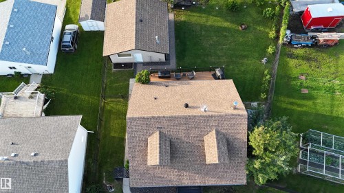 Expansive backyard featuring a wood deck with black railing, a detached shed, and a large grassy area - 4508 57 Avenue, Lamont, AB - Outdoor