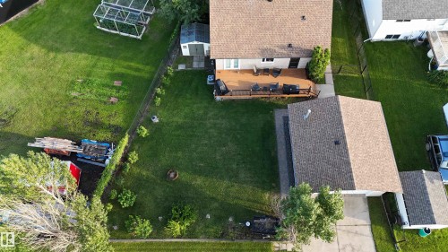Expansive residential lot featuring a well-manicured lawn with mature landscaping, multiple outbuildings including a detached garage structure, and established shade trees throughout the property - 4508 57 Avenue, Lamont, AB - Outdoor