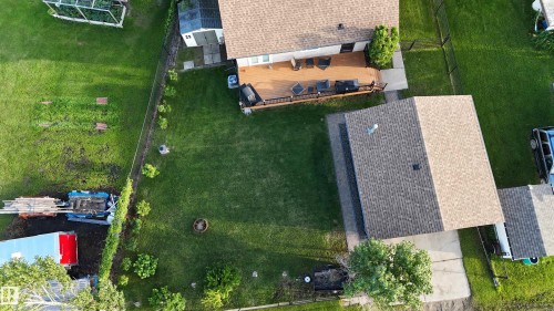 Expansive green lawn with a fire pit feature, bordered by a chain link fence and mature shrubbery - 4508 57 Avenue, Lamont, AB - Outdoor