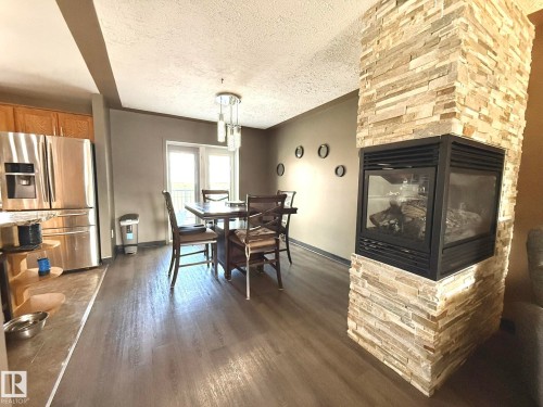 Stacked stone fireplace with a two-sided glass enclosure - 4508 57 Avenue, Lamont, AB - Indoor With Fireplace