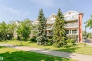 Multi-story residence featuring a combination of stucco and siding facade, multiple balconies with metal railings, gabled rooflines, and mature evergreen and deciduous trees - #106 12110 106 Av Nw, Edmonton, AB  - Outdoor 