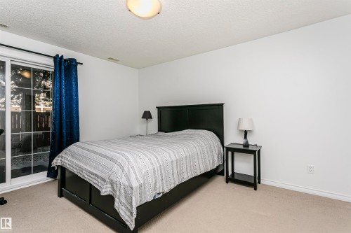 Carpeted room featuring a ceiling-mounted light fixture, white baseboards, and a glass sliding door - #106 12110 106 Av Nw, Edmonton, AB - Indoor Photo Showing Bedroom