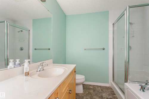 Bathroom featuring a single vanity with an integrated sink, light wood-finish cabinetry, and a large mirror - #106 12110 106 Av Nw, Edmonton, AB - Indoor Photo Showing Bathroom