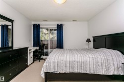 Carpeted room with white walls, featuring a sliding glass door, overhead lighting, and a built-in desk with shelving - 