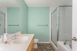 Bathroom featuring a shower-tub combination with glass enclosure, wood-finish vanity with an integrated sink, and a large wall-mounted mirror - 