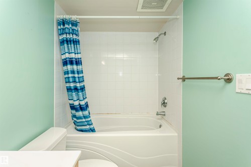White tiled shower-over-tub with chrome fixtures - #106 12110 106 Av Nw, Edmonton, AB - Indoor Photo Showing Bathroom