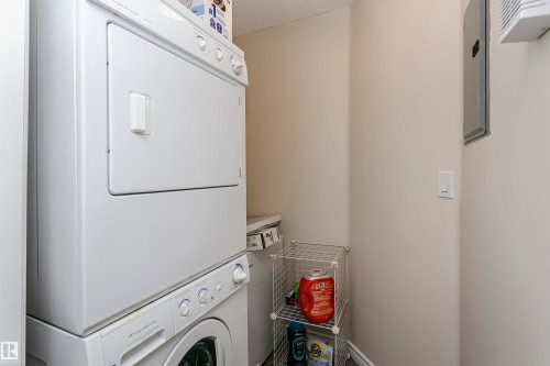 Dedicated laundry area featuring a white stackable washer and dryer unit - #106 12110 106 Av Nw, Edmonton, AB - Indoor Photo Showing Laundry Room