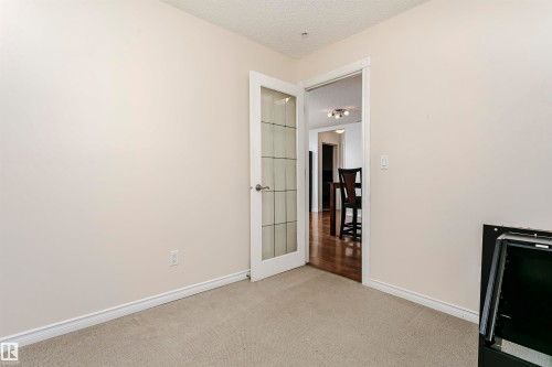 Interior room featuring light-toned walls, neutral carpet flooring, and white baseboards - #106 12110 106 Av Nw, Edmonton, AB - Indoor Photo Showing Other Room