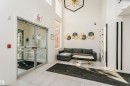 Spacious entry hall featuring double glass doors, high ceilings, large windows, and light-toned tile flooring - #106 12110 106 Av Nw, Edmonton, AB  - Indoor Photo Showing Other Room 