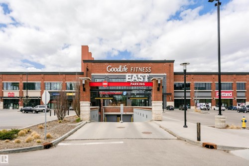 Commercial building featuring a brick exterior, multiple storefronts, and an integrated underground parking entrance - #106 12110 106 Av Nw, Edmonton, AB - Outdoor