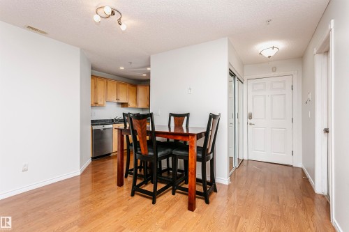 Open-concept living area featuring wood-finish flooring, a kitchen with light wood cabinetry, stainless steel appliances, and recessed lighting - #106 12110 106 Av Nw, Edmonton, AB - Indoor Photo Showing Dining Room