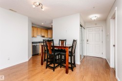 Open-concept living area featuring wood-finish flooring, a kitchen with light wood cabinetry, stainless steel appliances, and recessed lighting - 