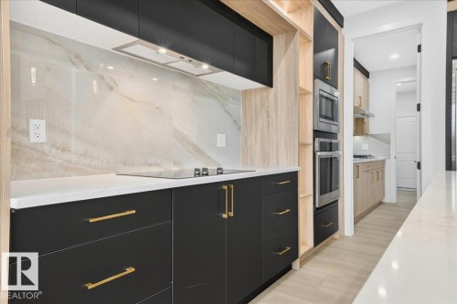 Contemporary kitchen featuring black cabinetry with gold-tone hardware, a white countertop, and a full-height backsplash with natural stone veining - 427 172 Avenue Nw, Edmonton, AB - Indoor Photo Showing Bathroom