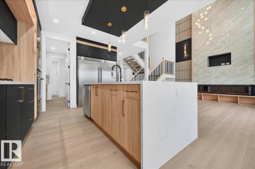 Gourmet kitchen featuring a large island with a waterfall counter, stainless steel appliances, and two-tone cabinetry - 427 172 Avenue Nw, Edmonton, AB - Indoor Photo Showing Kitchen