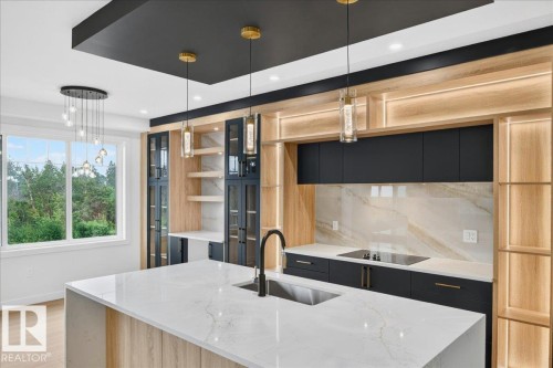 Contemporary kitchen featuring a large waterfall-edge island with an undermount sink and black faucet - 427 172 Avenue Nw, Edmonton, AB - Indoor Photo Showing Kitchen With Upgraded Kitchen
