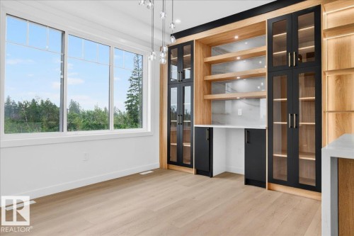 Integrated custom cabinetry featuring wood-finish framing, black glass-front doors, and open shelving with under-shelf lighting - 427 172 Avenue Nw, Edmonton, AB - Indoor Photo Showing Other Room