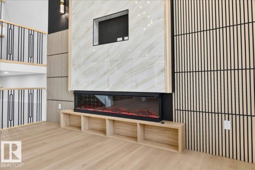 Feature wall showcasing a linear electric fireplace with integrated shelving, large format tile surround, and built-in media niche - 427 172 Avenue Nw, Edmonton, AB - Indoor Photo Showing Other Room With Fireplace