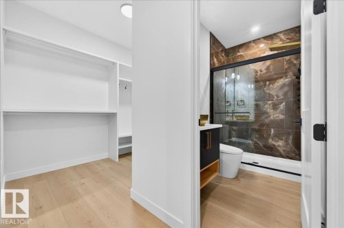 Walk-in closet featuring white built-in shelving, hanging rods, and wood-finish flooring - 427 172 Avenue Nw, Edmonton, AB - Indoor