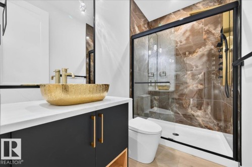 Contemporary bathroom featuring a gold vessel sink with matching gold-tone faucets, a dark vanity with gold-tone hardware, and a white countertop - 427 172 Avenue Nw, Edmonton, AB - Indoor Photo Showing Bathroom