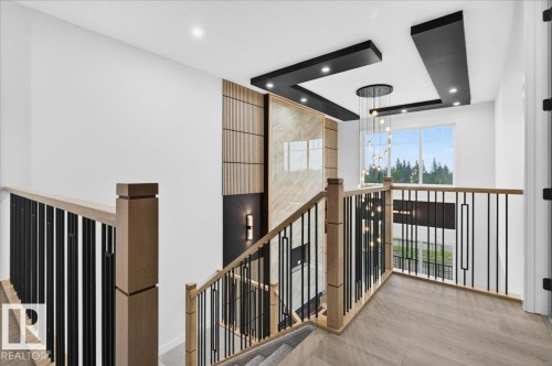 Staircase featuring wood-finish railings with black metal balusters, textured wall paneling, recessed lighting, and a contemporary multi-pendant chandelier - 427 172 Avenue Nw, Edmonton, AB -  Photo Showing Other Room