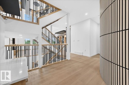 Multi-level interior featuring light wood-finish flooring, white walls, and a contemporary staircase with black and wood railings - 427 172 Avenue Nw, Edmonton, AB - Indoor Photo Showing Other Room