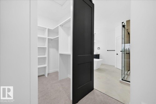 Walk-in closet with built-in shelving, carpet flooring, and a sliding barn door - 427 172 Avenue Nw, Edmonton, AB - Indoor