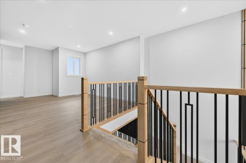 Open concept space featuring light wood-finish flooring, recessed lighting, and a modern staircase with wood handrails and black metal balusters - 427 172 Avenue Nw, Edmonton, AB - Indoor Photo Showing Other Room