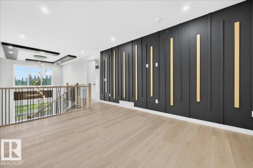 Upper-level landing featuring wood-finish flooring, a modern black accent wall with vertical wood paneling, and a contemporary open-spindle railing - 427 172 Avenue Nw, Edmonton, AB - Indoor Photo Showing Other Room