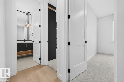 Hallway featuring light wood-finish flooring, white walls, and white doors with matte black hardware - 427 172 Avenue Nw, Edmonton, AB - Indoor Photo Showing Other Room