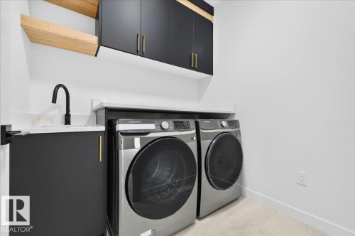 Dedicated laundry area featuring a countertop with an integrated sink, matte black faucet, and modern cabinetry with gold-toned hardware - 427 172 Avenue Nw, Edmonton, AB - Indoor Photo Showing Laundry Room