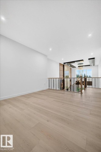 Expansive open space with light wood-finish flooring, recessed ceiling lighting, and a modern metal railing overlooking a lower level - 427 172 Avenue Nw, Edmonton, AB - Indoor Photo Showing Other Room