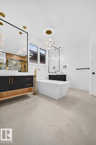 Freestanding soaking tub with a floor-mounted gold-finish faucet - 427 172 Avenue Nw, Edmonton, AB - Indoor Photo Showing Other Room