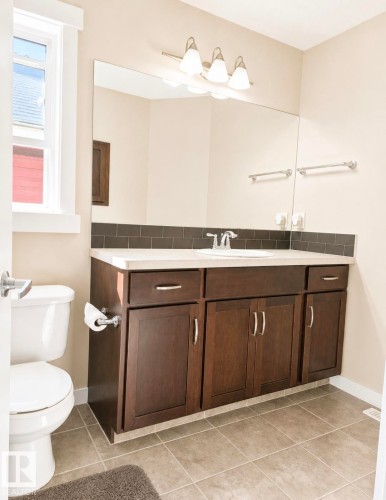 Bathroom featuring a spacious vanity with dark wood-finish cabinetry, a white countertop, and a white undermount sink - 5135 1A Avenue Sw, Edmonton, AB - Indoor Photo Showing Bathroom
