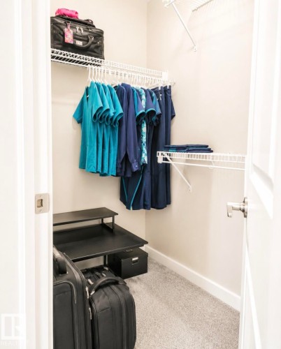 Carpeted walk-in closet featuring white wire shelving, a hanging rod system, and neutral wall tones - 5135 1A Avenue Sw, Edmonton, AB - Indoor With Storage