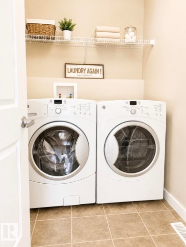 Dedicated laundry area featuring a front-loading washer and dryer set, wire shelving, and neutral wall paint - 5135 1A Avenue Sw, Edmonton, AB - Indoor Photo Showing Laundry Room
