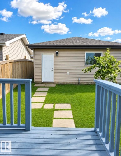 Spacious backyard featuring a manicured lawn, a stepping stone pathway, and a light blue deck - 5135 1A Avenue Sw, Edmonton, AB - Outdoor